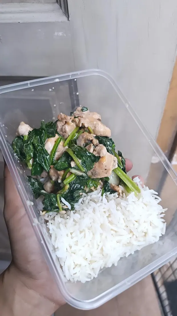 A meal prep box held in hand, chicken with spinach and rice